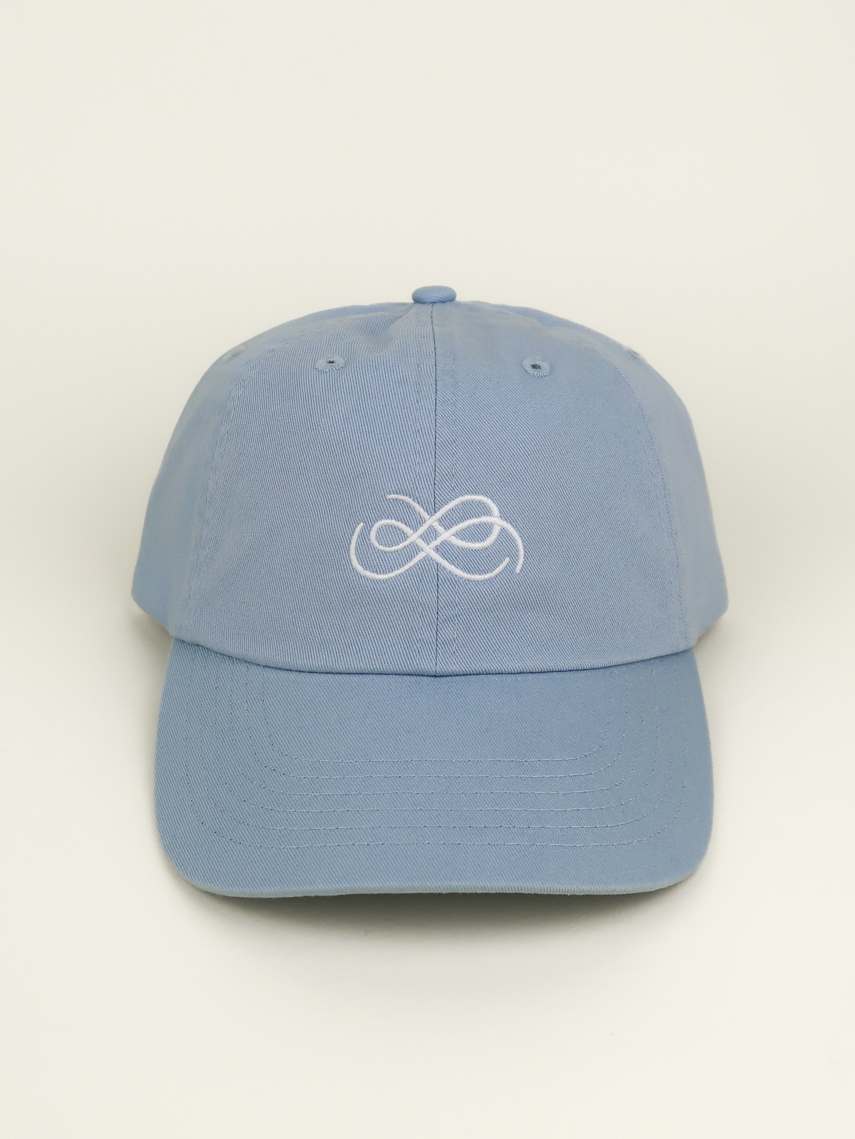 Blue cap with From Sea To Sol logo symbol on a beige background