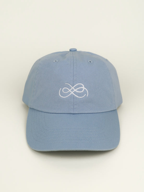 Blue cap with From Sea To Sol logo symbol on a beige background